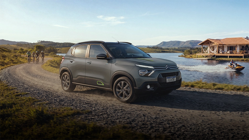 Viva a atitude SUV do Citroën XTR Citroën C3 XTR na cor prata trafegando por uma estrada de terra e pedras, num cenário campestre, com muita vegetação e árvores, sob luz natural.