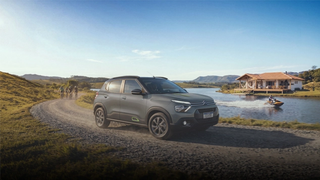Citroën C3 XTR na cor prata trafegando por uma estrada de terra e pedras, num cenário campestre, com muita vegetação e árvores, sob luz natural.
