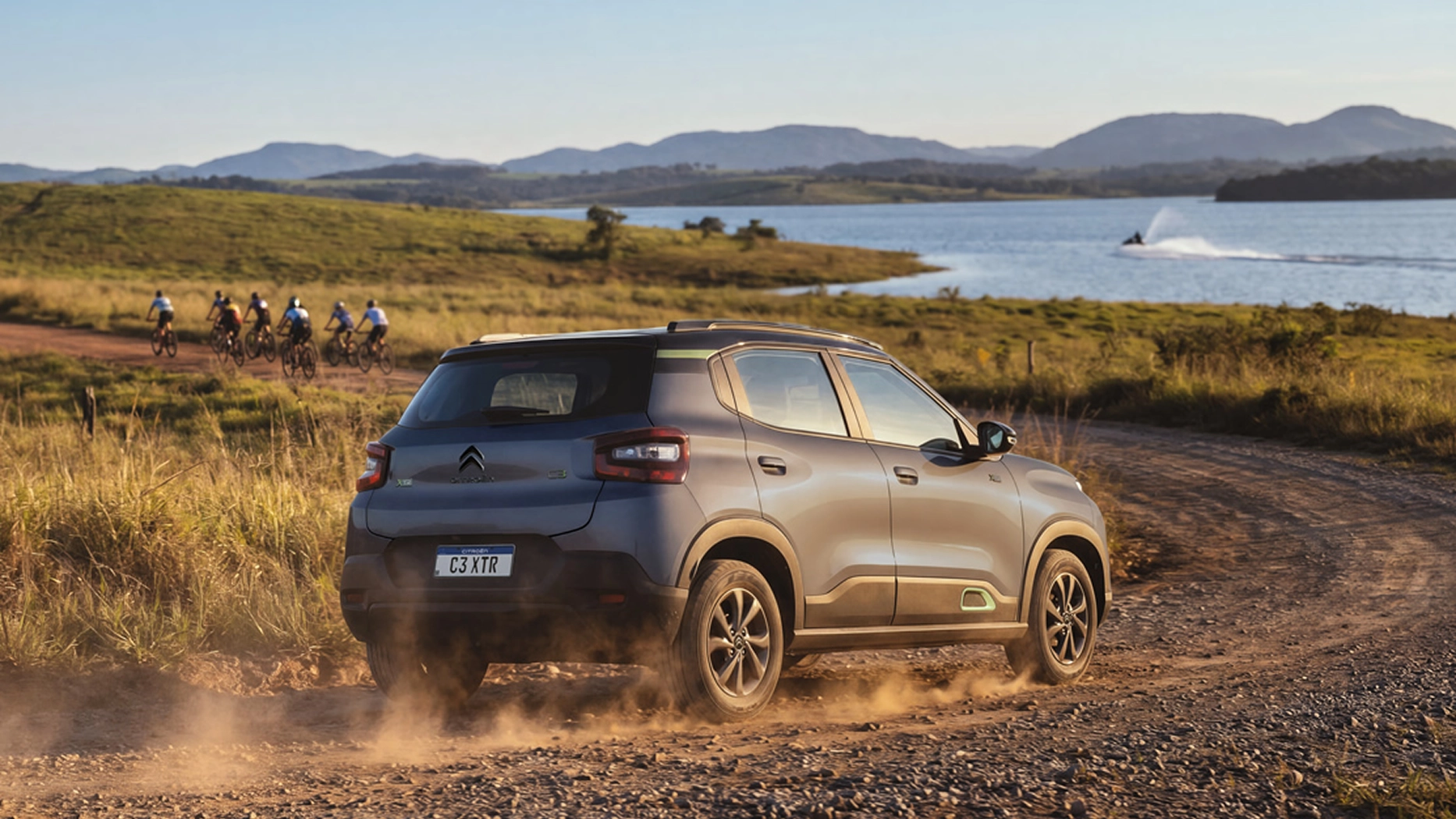 Citroën C3 XTR na cor prata trafegando por uma estrada de terra e pedras, num cenário campestre, com muita vegetação e árvores, sob luz natural.