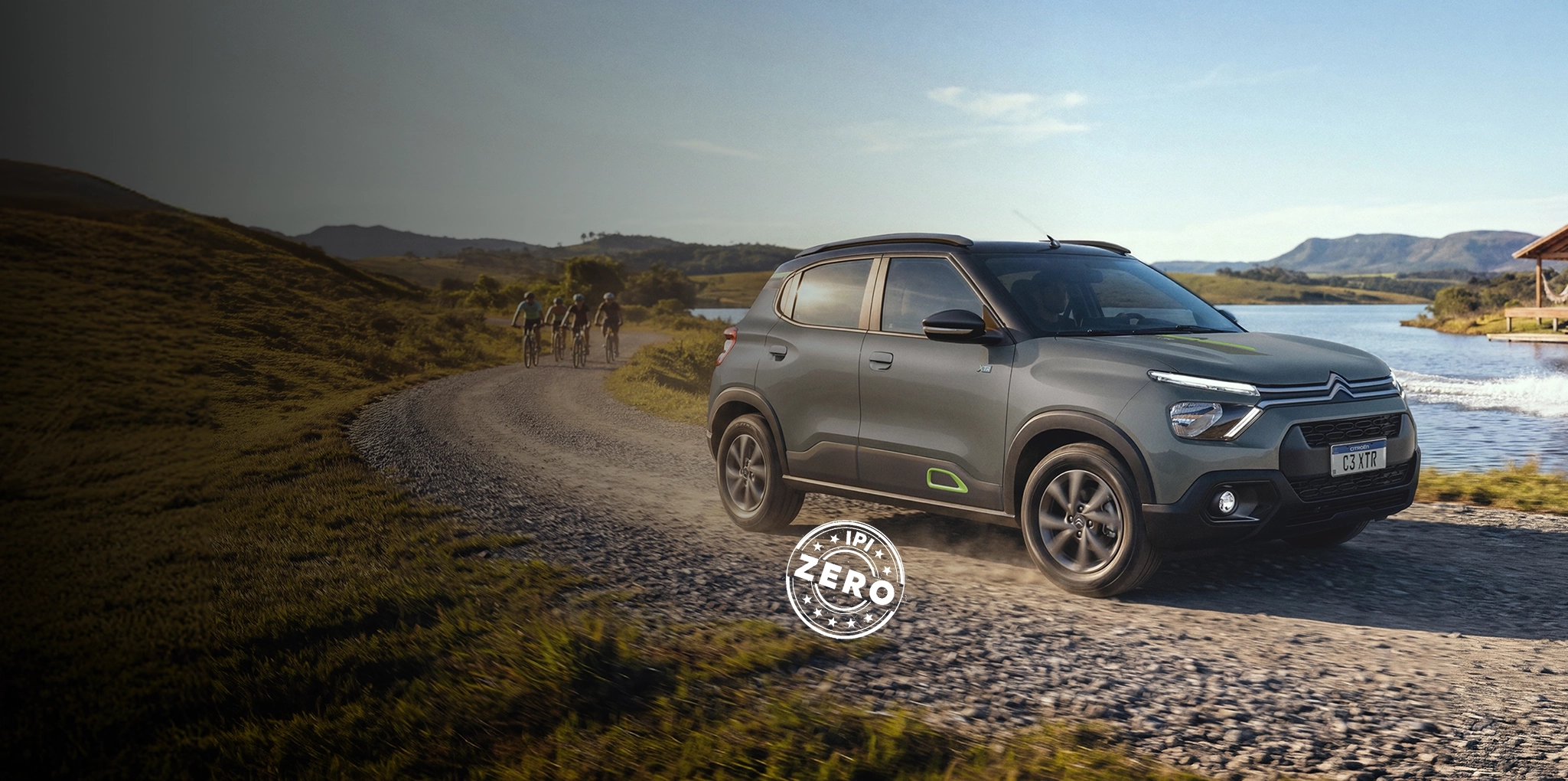 Citroën C3 XTR na cor prata trafegando por uma estrada de terra e pedras, cercado por vegetação e árvores, sob luz natural.