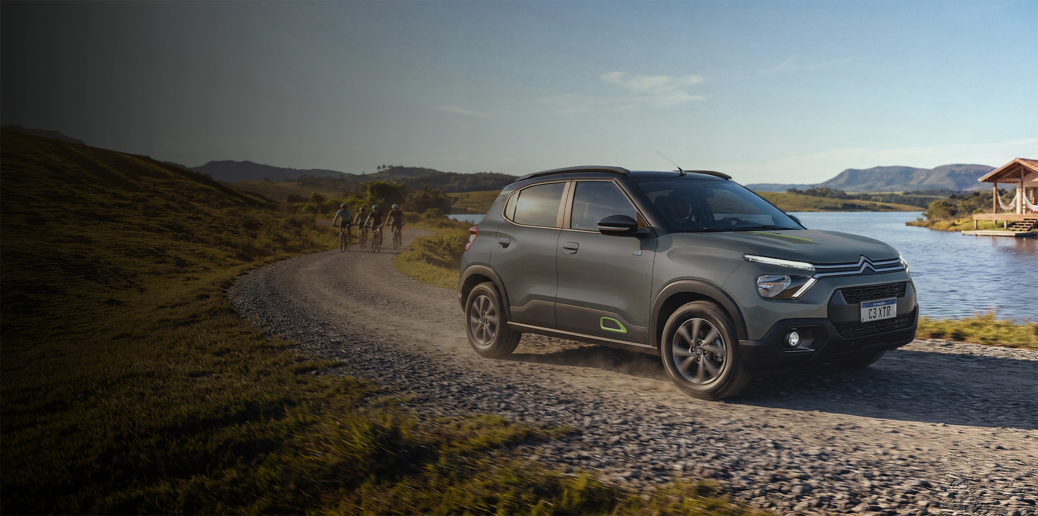 Citroën C3 XTR para ir além do asfalto Citroën C3 XTR na cor prata trafegando por uma estrada de terra e pedras, cercado por vegetação e árvores, sob luz natural.