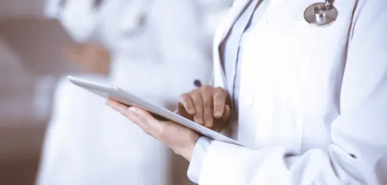 Foto de um homem branco vestindo jaleco fazendo anotações